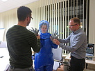 Eine Neuköllner THW-Helferin probiert einen Schutzanzug aus, der je nach Gefährdungslage getragen werden muss. Dr. Christian Herzog (re) und Dr. Karsten Arends (li) helfen beim Anziehen. Quelle: THW/ Anja Villwock