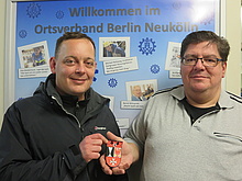 Christian Bärmann (li), BüroLeiter der Bezirksbürgermeisterin und Leiter des Alt-Rixdorfer Weihnachtsmarktes übergibt ein Neukölln-Wappen an den THW-Ortsbeauftragten Brookert Burri (re). Quelle: THW/ Anja Villwock