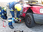 Nach einem Verkehrsunfall heben die THW-Helfer das Fahrzeug mit dem hydraulischen Spreizer an und füttern Holz unter, um das Wackeln des Autos zu verhindern. Quelle: THW/ Anja Villwock