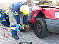 Nach einem Verkehrsunfall heben die THW-Helfer das Fahrzeug mit dem hydraulischen Spreizer an und füttern Holz unter, um das Wackeln des Autos zu verhindern. Quelle: THW/ Anja Villwock