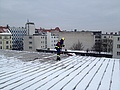Mit Auffanggurt und Leine gesichert, beseitigen die Helfer gefährliche Schneebretter von den Dächern Berlins. Foto: THW/Darian Hasshoff