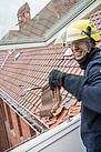 Ein Neuköllner THW-Helfer sammelt die Dachziegel aus dem Schneefanggitter ein. Quelle: THW/Anja Villwock