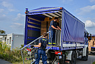 Die Ehrenamtlichen vom THW laden Betten, Matratzen, Stühle und Tische von ihren Lastwagen. Quelle: THW/ Andreas Wünsch