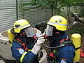 Gegenseitige Unterstützung beim Anlegen der Atemschutzgeräte. Foto: THW/Tobias Hahn